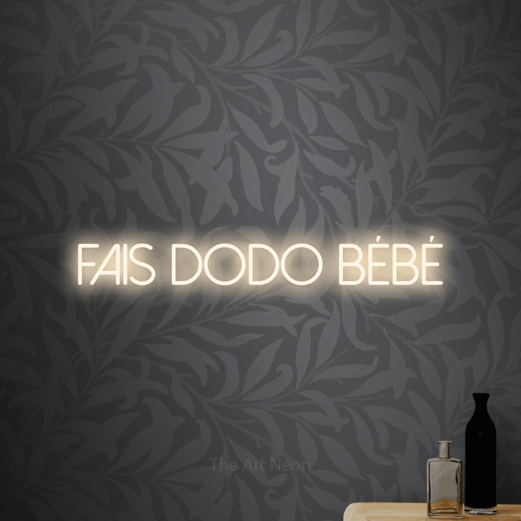 “Fais dodo bébé” LED neon sign in warm white, with thin sans-serif lettering, shown against grey botanical wallpaper.
