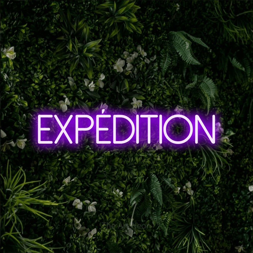 “Expédition” LED neon sign in purple, with thin sans-serif lettering, shown against a dense green plant wall.