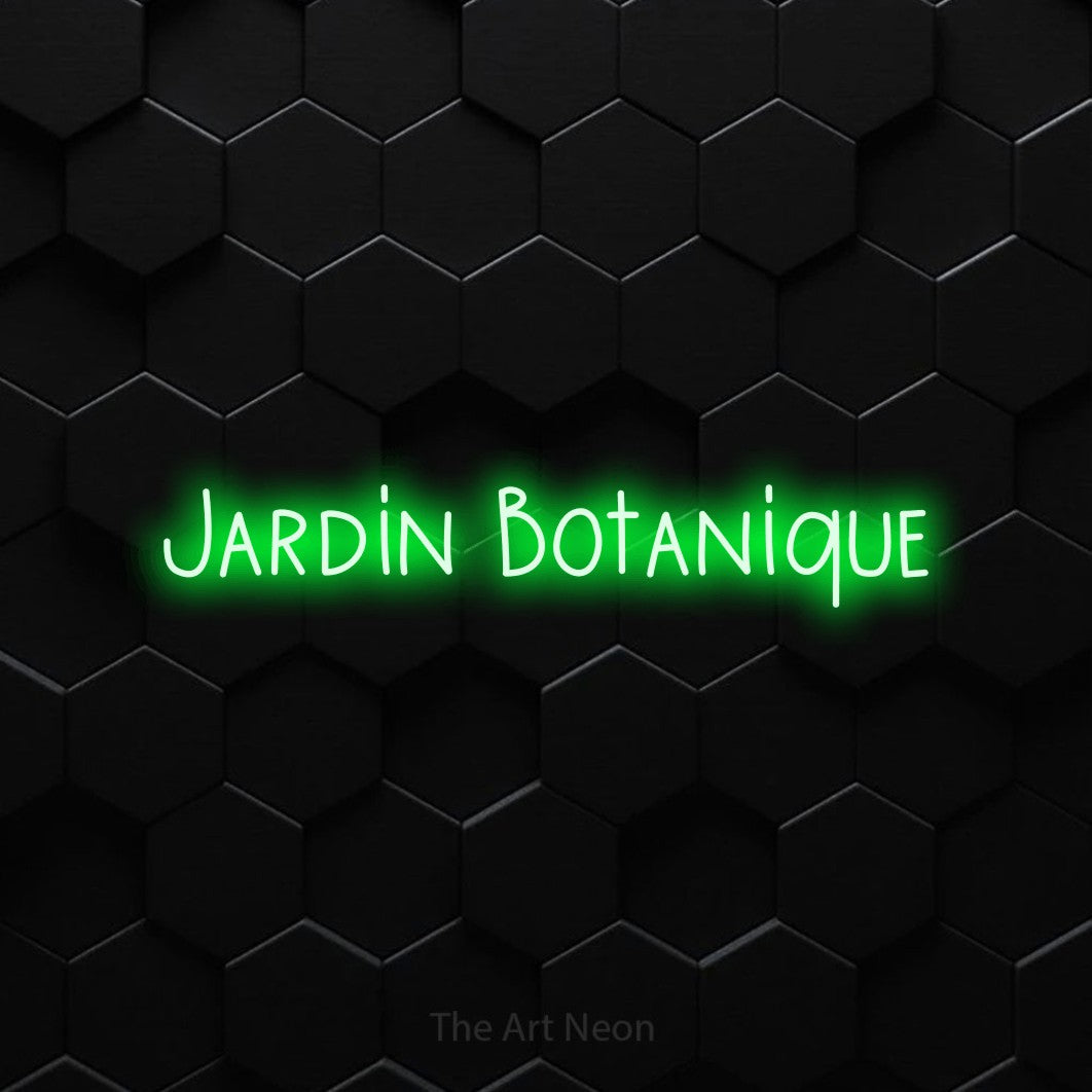 “Jardin botanique” LED neon sign in green, with narrow hand-drawn lettering, shown against black hexagonal wall tiles.