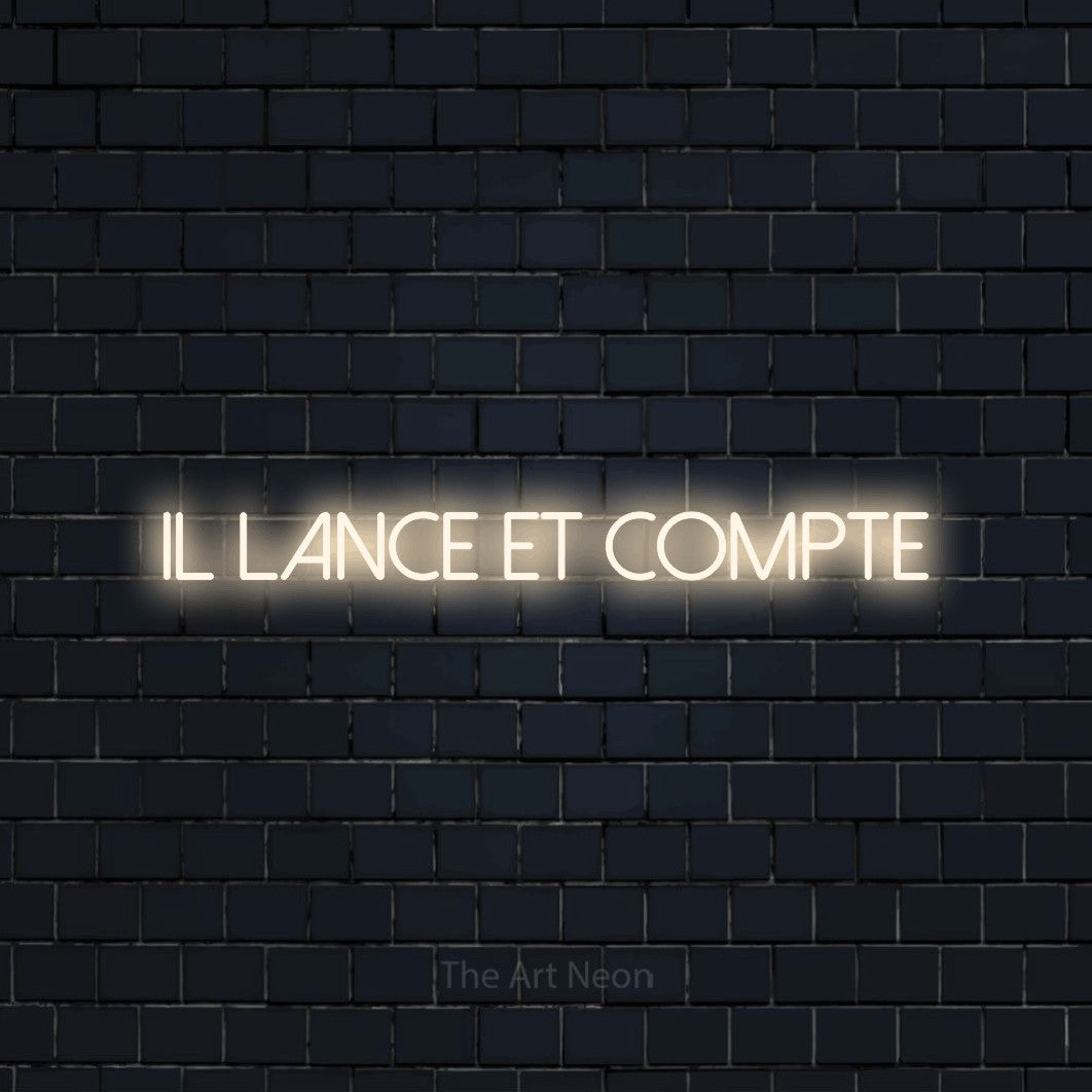 “Il lance et compte” LED neon sign in warm white, with thin sans-serif lettering, shown against a dark navy brick wall.