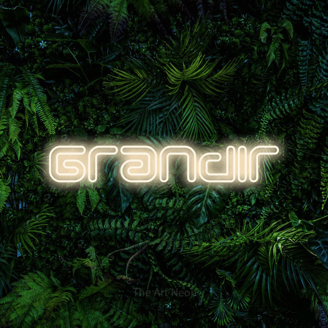 “Grandir” LED neon sign in warm white, with futuristic double-line lettering, shown against dense tropical foliage.