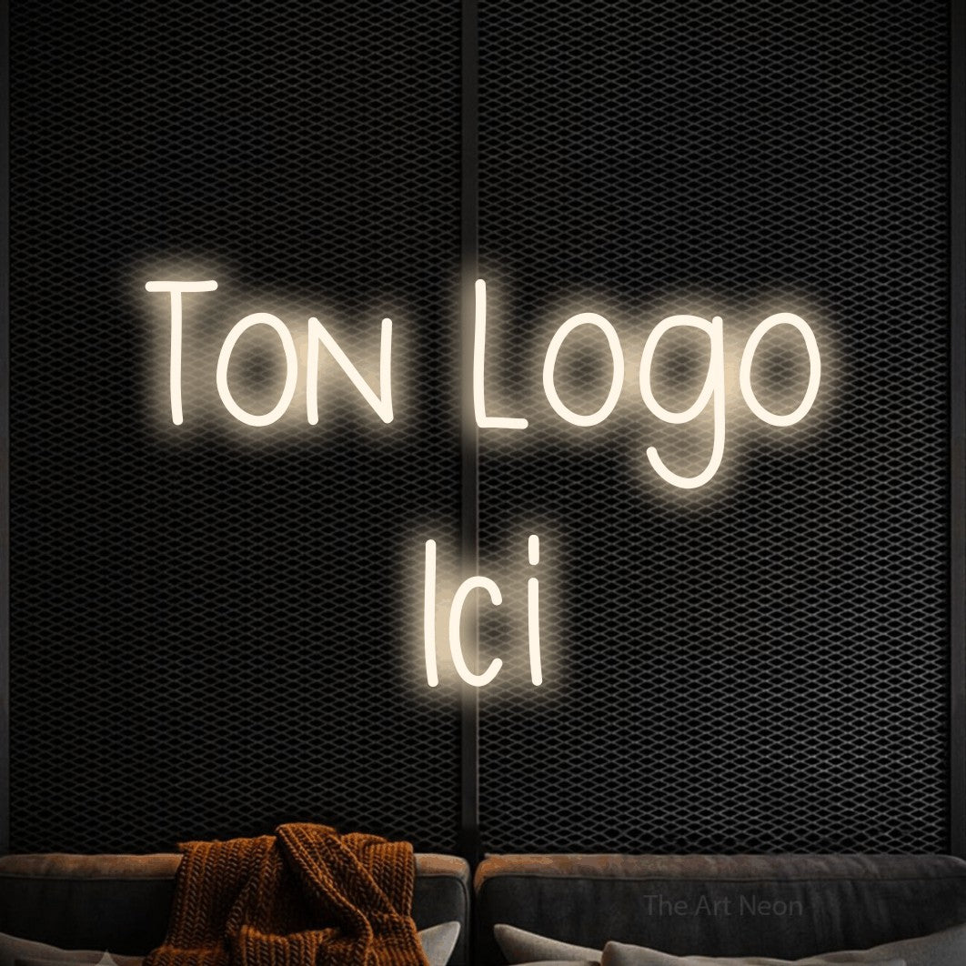 “Ton logo ici” LED neon sign in warm white, with narrow hand-drawn lettering across 2 lines, shown against a modern dark-toned seating area.