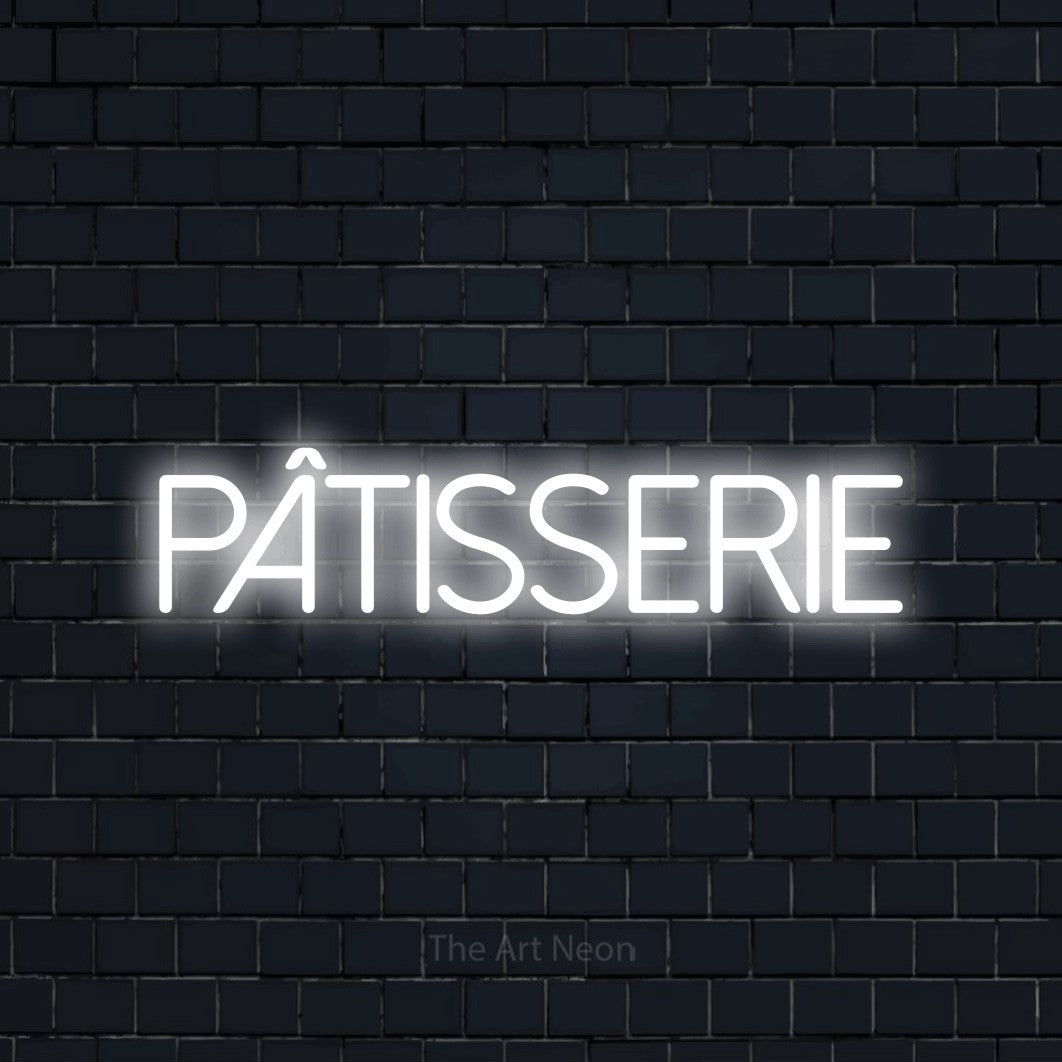 “Pâtisserie” LED neon sign in cool white, with thin sans-serif lettering, shown against a dark navy brick wall.
