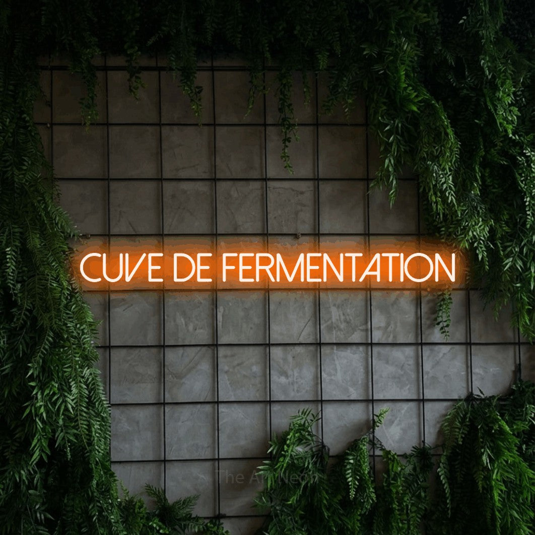 “Cuve de fermentation” LED neon sign in orange, with thin sans-serif lettering, shown against an ivy-covered concrete grid.