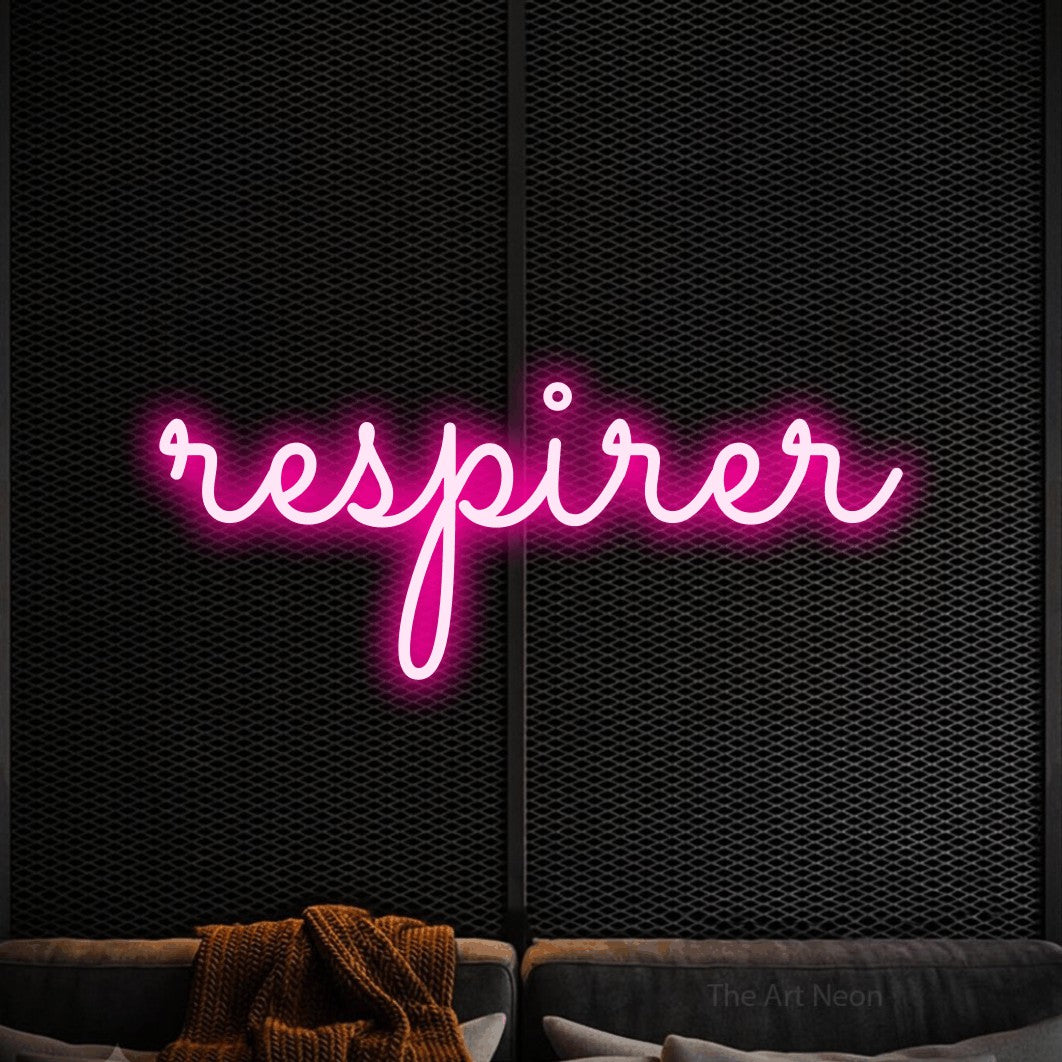 “Respirer” LED neon sign in hot pink, with looped cursive lettering, shown against a modern dark-toned seating area.